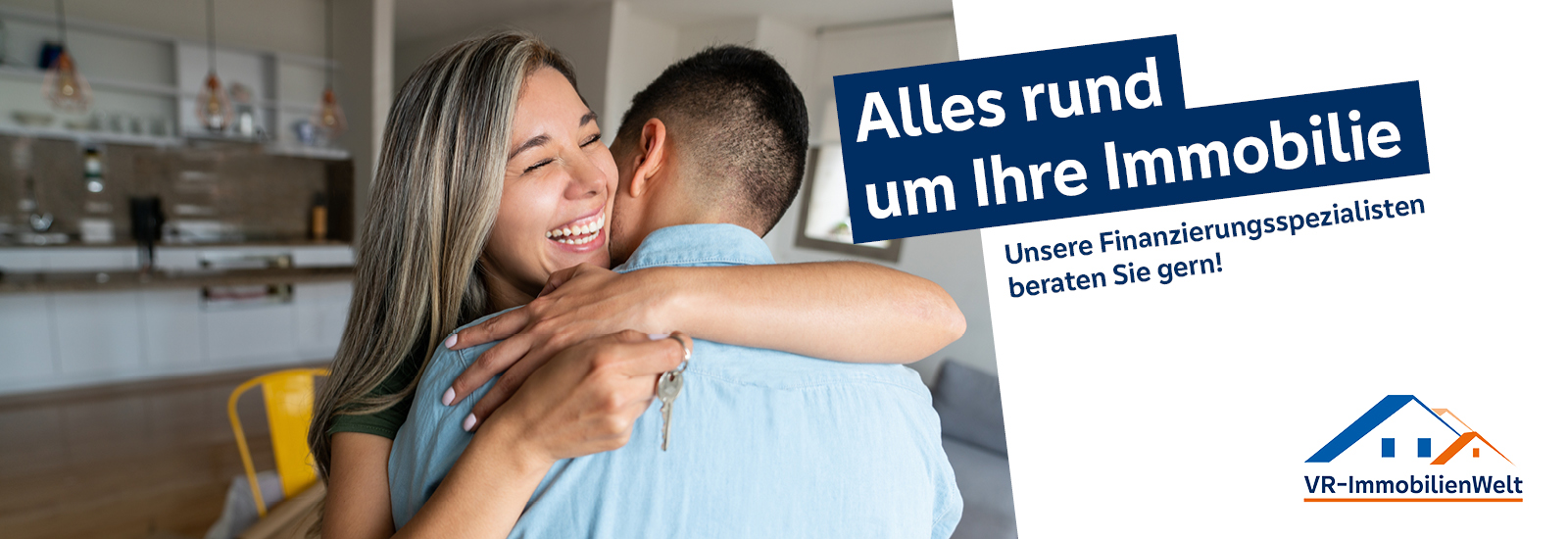 Zwei Personen umarmen sich in einem modernen Wohnraum, Text: 'Alles rund um Ihre Immobilie. Unsere Finanzierungsspezialisten beraten Sie gern! VR-ImmobilienWelt.'